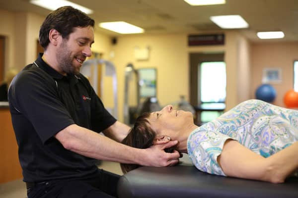 Physiotherapist performing cervical traction therapy on a patient in a clinic setting.