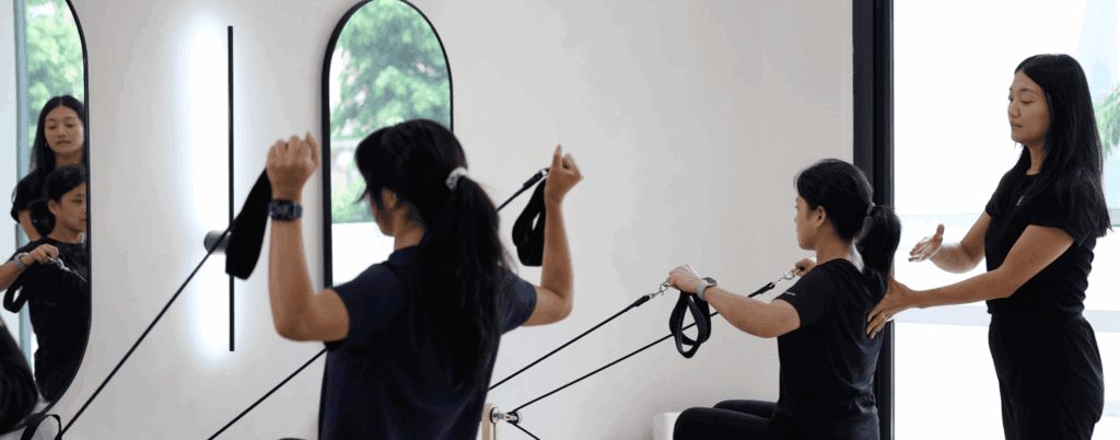 Postnatal women performing reformer Pilates exercises in a physiotherapy studio.