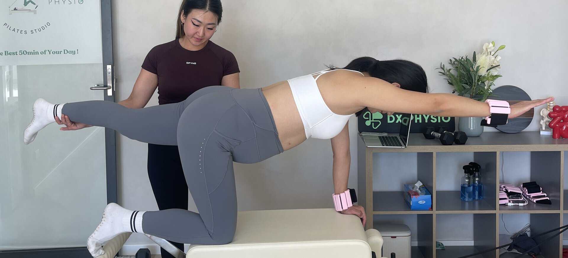 Physiotherapist guiding a woman through abdominal separation recovery exercises in a clinic.