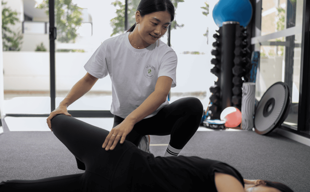 DX Physio + Reformer Pilates physiotherapist assisting a client during a session.